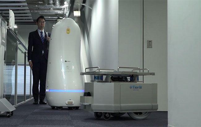 業務を終えた案内ロボットはエレベータで2階へ向かう。物流用ロボットは2階のオープンスペースで利用者に本を届けた後、エレベータホールへ移動